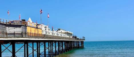 A pier extending into the sea with a sandy beach at the end.