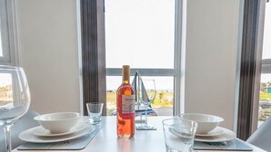 Taula de dinar posta amb plats, cuplets i vasos blancs, una ampolla de licor i un got de vi.