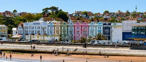 A beachfront hotel with colorful buildings, a sandy beach, and a clear sky.