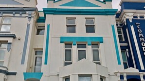 Un edifici de diversos pisos amb una entrada destacada i una escala que condueix a la planta baixa.