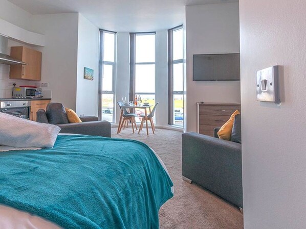 Un dormitorio moderno con una cama grande, un escritorio y vistas a través de una ventana.