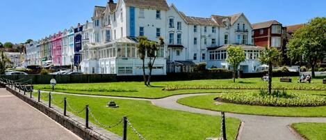 A row of colorful Victorian-style buildings with a well-maintained garden and a paved walkway.
