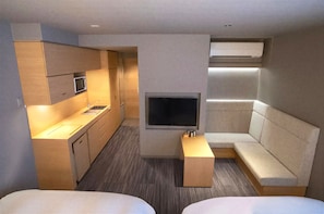 A compact hotel room with a kitchenette, a flat-screen TV, a sofa, and two beds. - Oaks Vacation Club Kyoto Shijo (Kyoto)