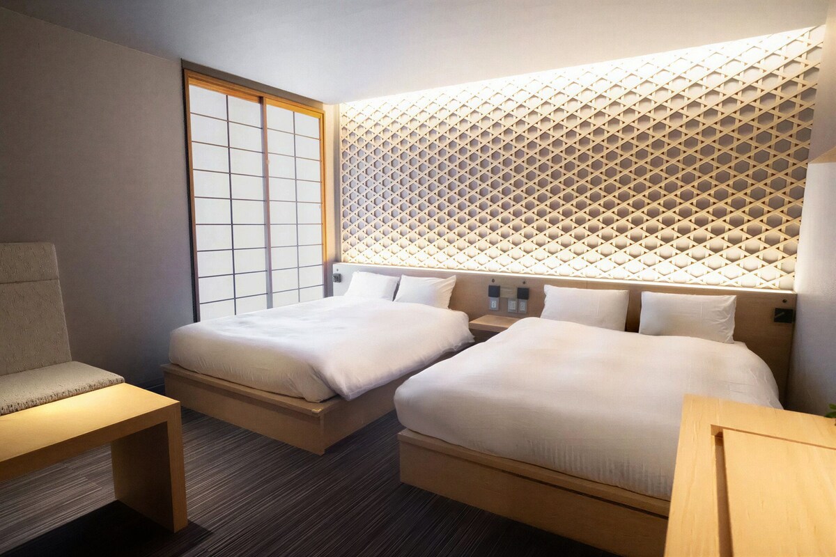 A hotel room with two beds, a seating area, and a traditional Japanese shoji screen.