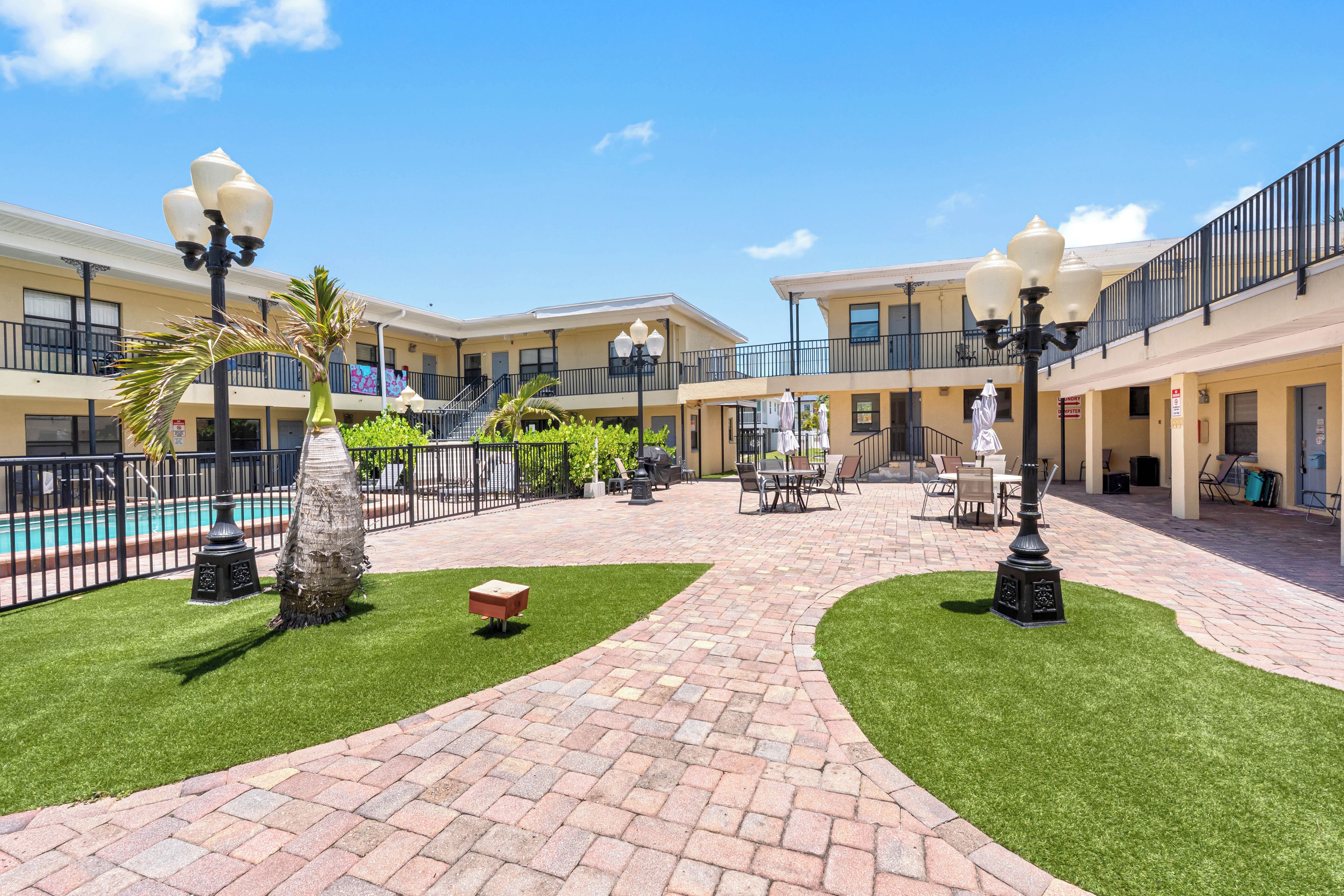 A courtyard with a swimming pool, palm trees, and outdoor seating areas.
