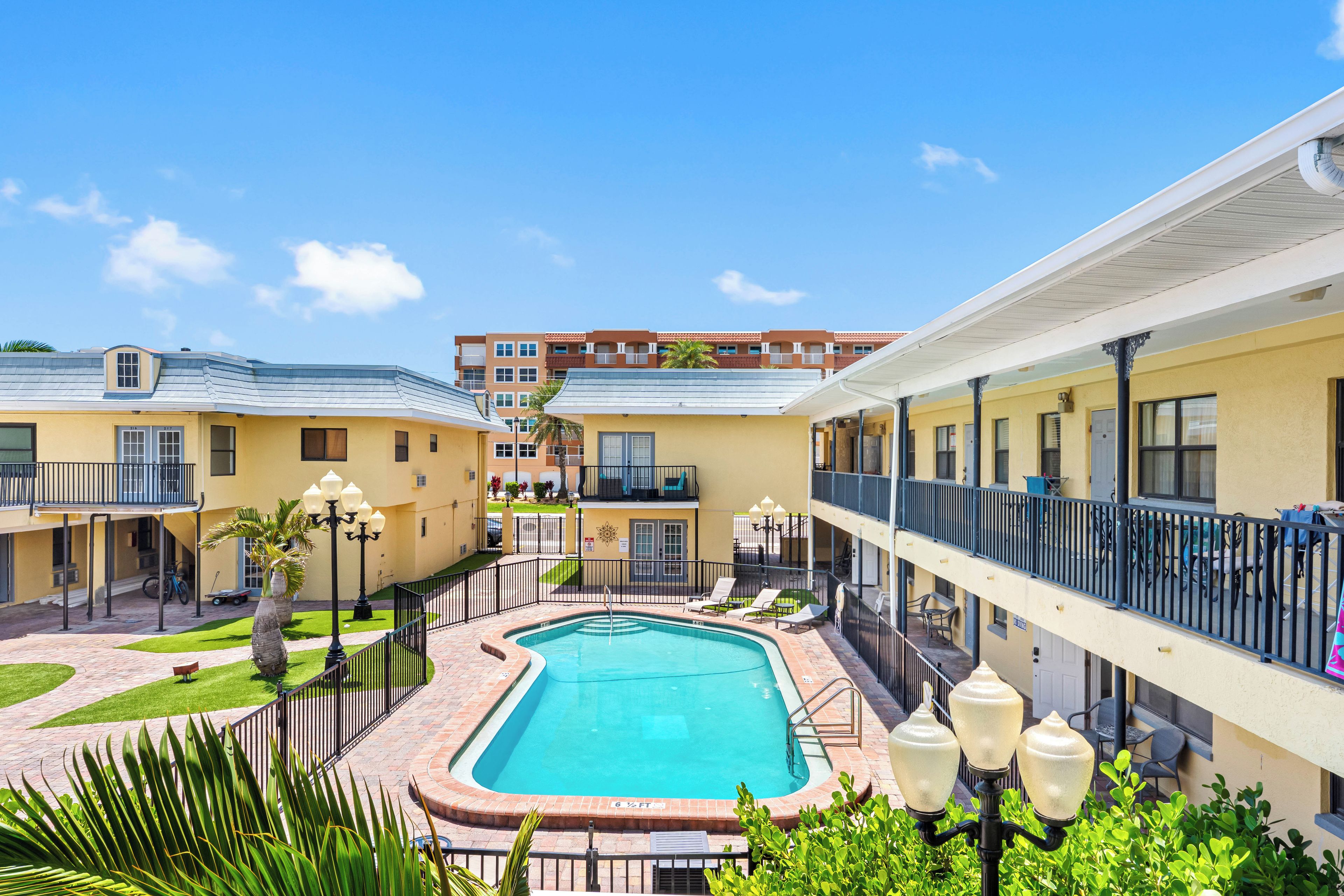A hotel with a swimming pool, outdoor seating, and a view of the surrounding buildings.