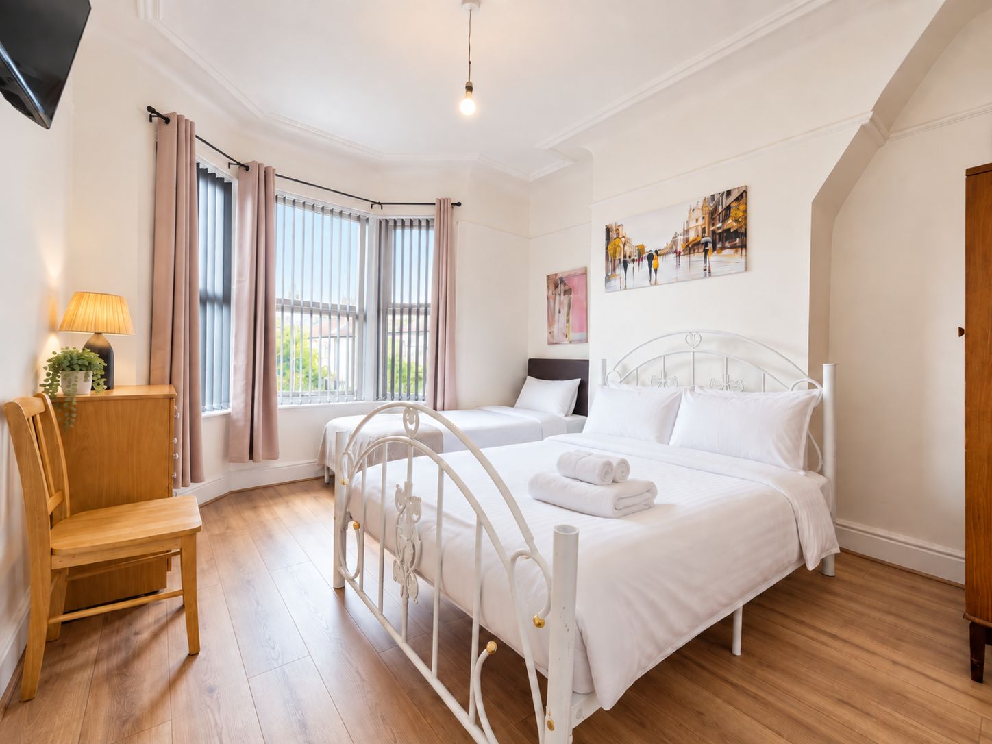 A hotel room with a bed, a chair, a desk, a lamp, and a window with curtains.