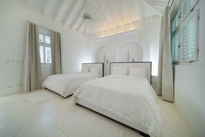 A bedroom with two beds, a ceiling fan, and a large window with curtains. - Walk to beach. Luxury Mediterranean villa includes golf cart. (La Romana)