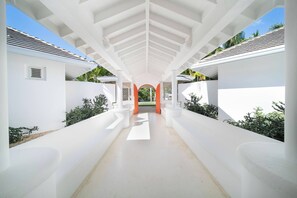 A modern architectural structure with a central walkway leading to an orange archway. - Walk to beach. Luxury Mediterranean villa includes golf cart. (La Romana)