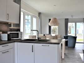 A modern kitchen with white cabinetry, a built-in microwave, and a large window.