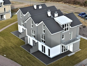 A modern multi-story residential building with a flat roof, large windows, and a balcony. - House No. 16, Deichgraf (Wangerland)