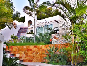 Ein modernes Haus mit einer Steinwand, einer Treppe und tropischen Pflanzen.