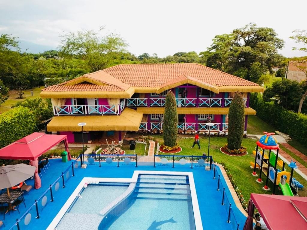 Un hotel con piscina, parque infantil y jardín bien cuidado.