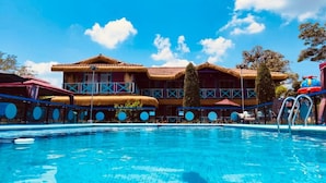 Un hôtel doté d’une piscine, d’un bâtiment à toit de chaume et surplombant un ciel d’un bleu éclatant.