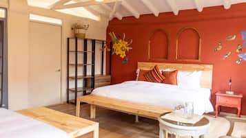 Une chambre à coucher comprenant un lit, un banc en bois, une petite table, une table de chevet et une étagère.