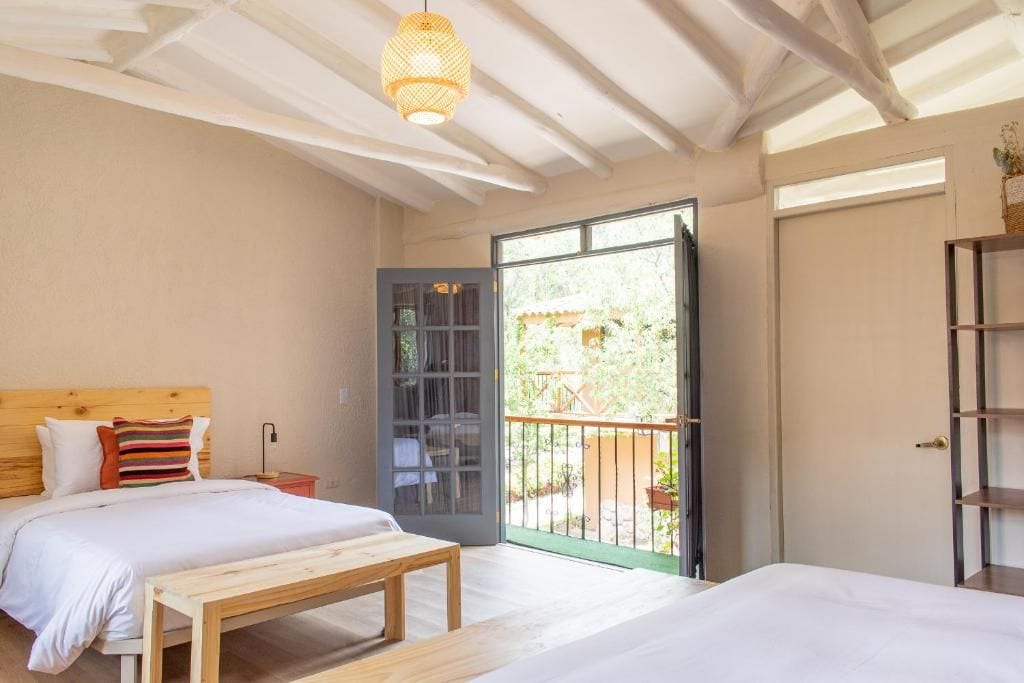 Une chambre à coucher comprenant un lit, un banc, une table de chevet et une porte donnant sur un balcon.