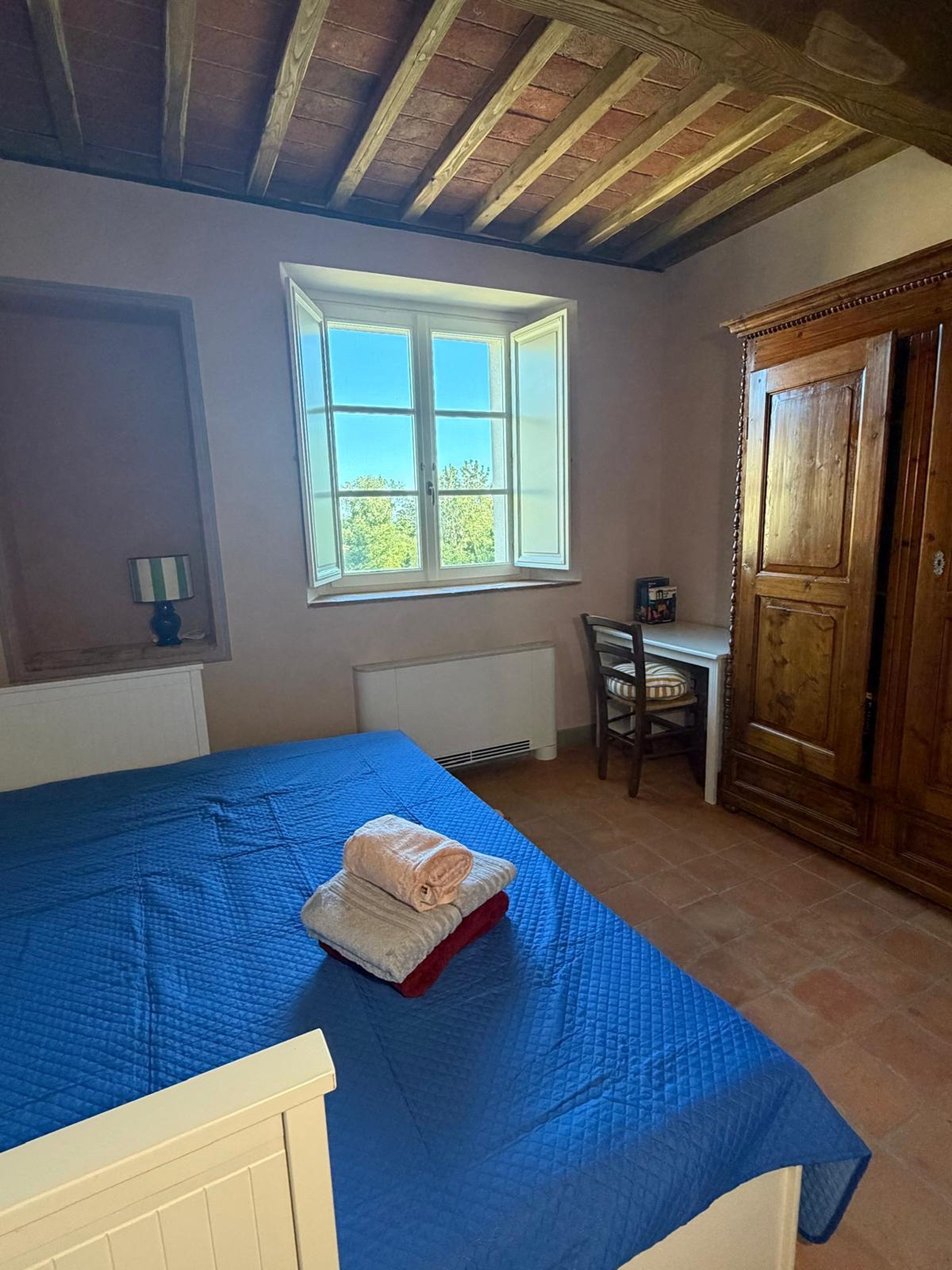Une chambre à coucher avec un lit, une fenêtre, un bureau et une armoire.