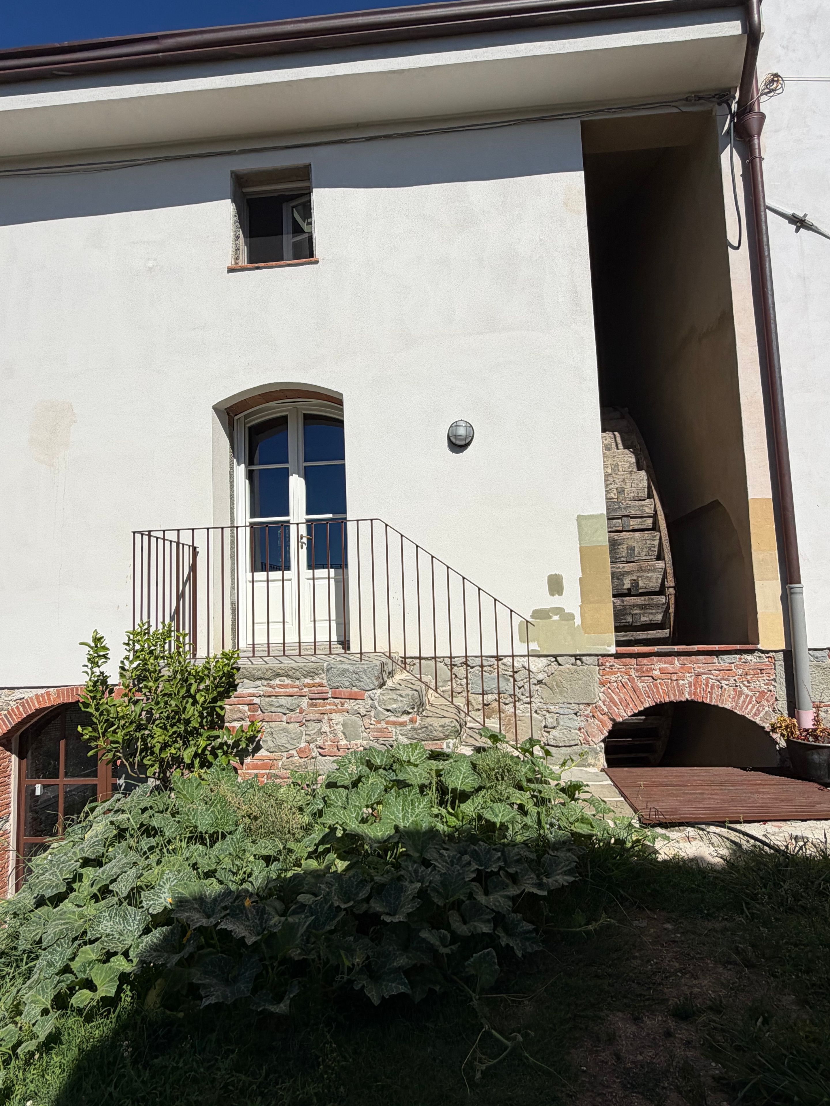 Un bâtiment doté d’un escalier en pierre menant à une porte, d’une petite fenêtre et d’un luminaire placé au-dessus de la porte.
