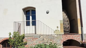 A building with a stone staircase leading to a door, a small window, and a light fixture above the door.