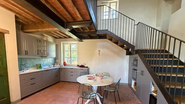 A kitchen with a dining table and chairs, a staircase, and a view of the outdoors. - Holiday Home 'Tuscany Terroir' with Private Garden, Wi-Fi and Air Conditioning (Capannori)