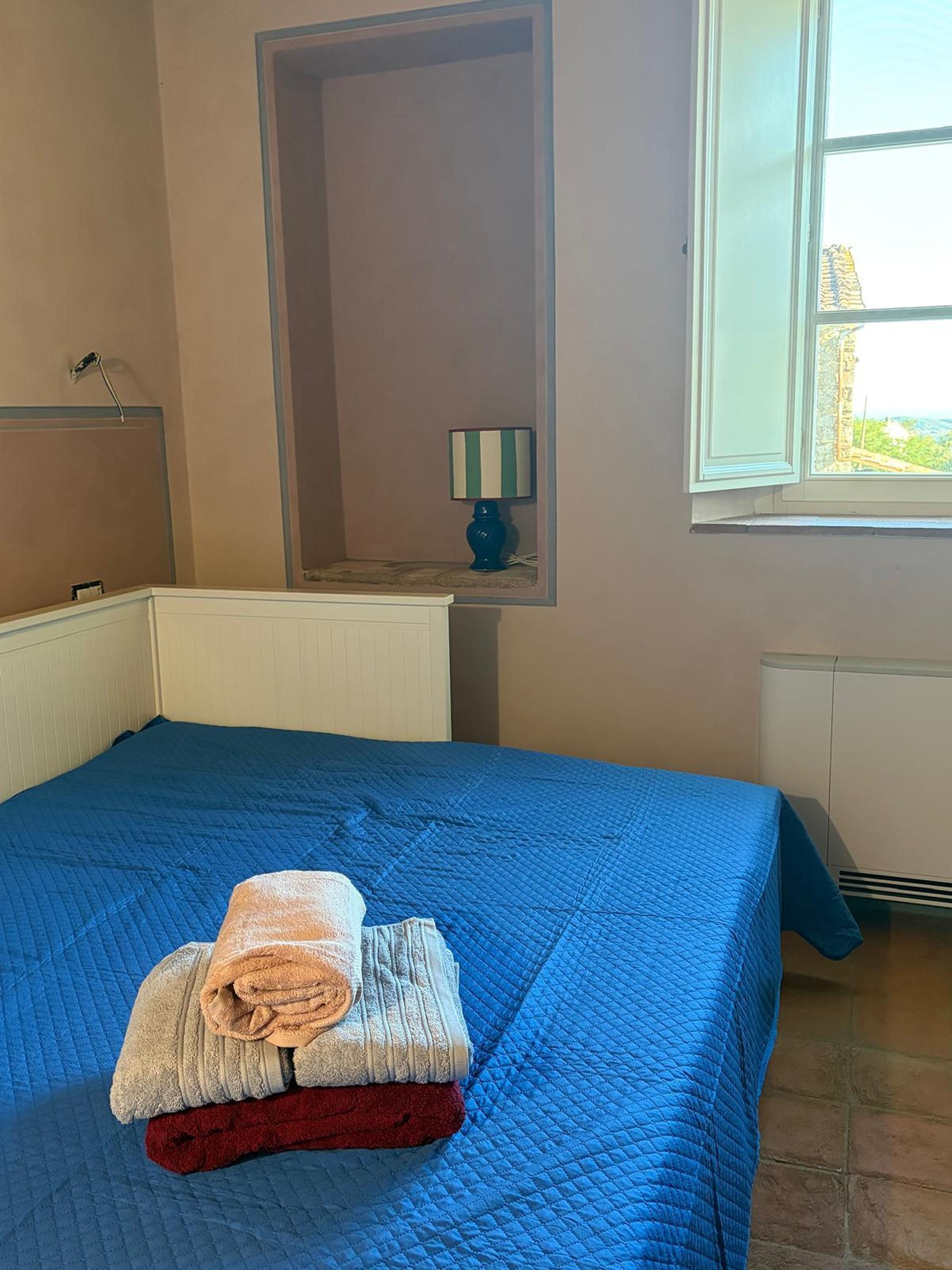 A room with a bed, a window, a radiator, and a lamp.