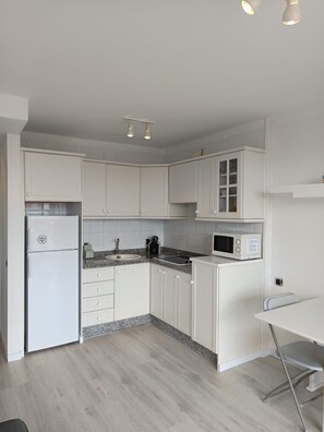 A modern kitchen with white cabinetry, a built-in microwave, and a stainless steel refrigerator. - DANICO PLAYA HONDA 51/C (Playa de las Américas)
