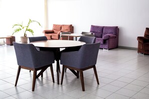 A modern interior with a round table surrounded by chairs, a sofa, and a purple armchair. - DANICO PLAYA HONDA 51/C (Playa de las Américas)