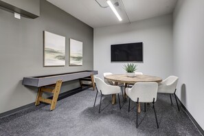 Een vergaderruimte met een pooltafel, een ronde tafel met stoelen, en twee kunstwerken aan de muur.