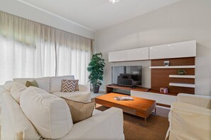 Een moderne woonkamer met een bank, salontafel, televisie en ingebouwde planken.