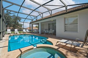 An outdoor swimming pool with a glass enclosure, surrounded by lounge chairs and a patio area. - Windsor Hills 5BR Home Near Disney Parks (Kissimmee)