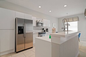 A modern kitchen with a stainless steel refrigerator, a built-in oven, and a microwave. - Windsor Hills 5BR Home Near Disney Parks (Kissimmee)