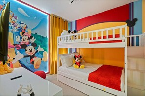 Een kinderkamer met een stapelbed, een Mickey Mouse knuffel en een muurschildering van Disney personages.