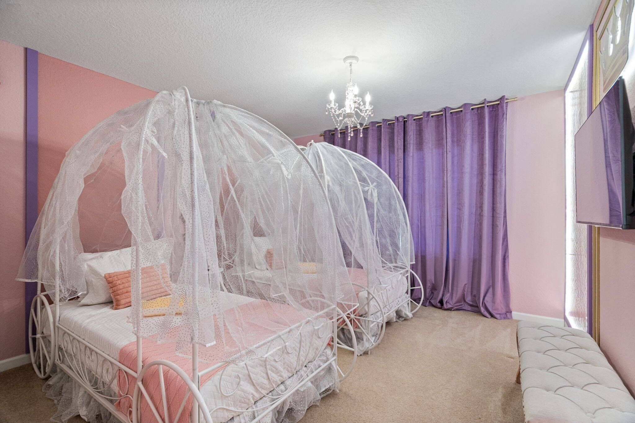 Ein Zimmer mit Himmelbett, einer Kristallleuchtre und violetten Vorhängen.