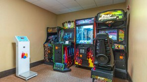 A row of arcade games including 'Aliens', 'Hot Streak', and 'The Fast and the Furious' in a room with beige walls and carpeted flooring. - Harry Potter Apartment Near Universal (Orlando)