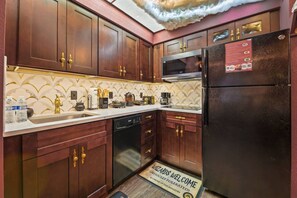 A kitchen with wooden cabinets, a black refrigerator, a microwave, and a dishwasher. - Harry Potter Apartment Near Universal (Orlando)