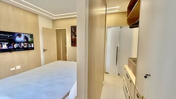 A hotel room with a large bed, a flat-screen TV mounted on the wall, and a modern design with neutral colors.