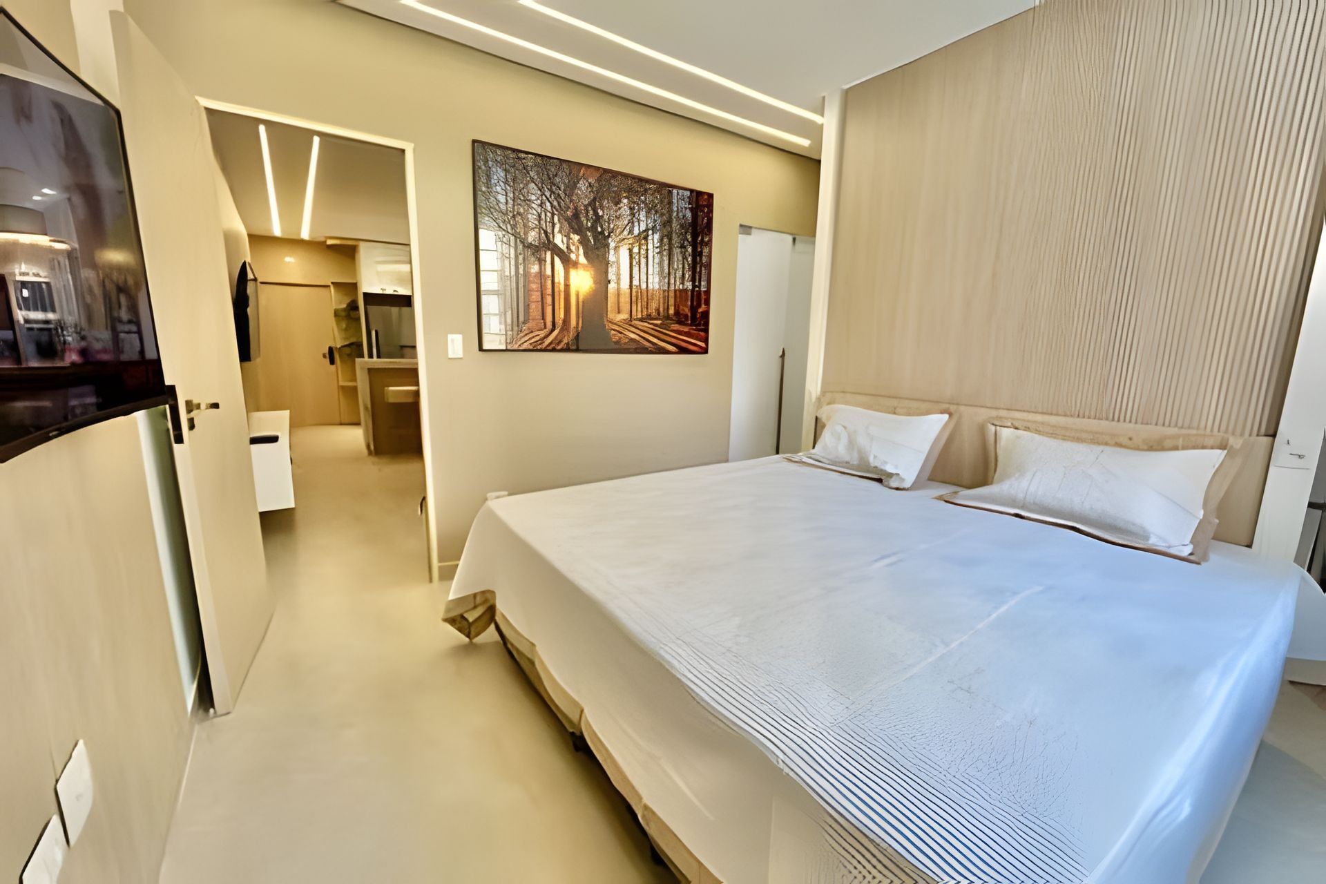 Una habitación de hotel moderna con una cama grande, un cuadro en la pared y un cabecero de madera.