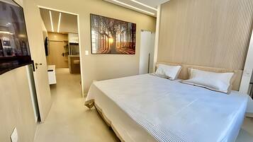 Una habitación de hotel moderna con una cama grande, un cuadro en la pared y un cabecero de madera.