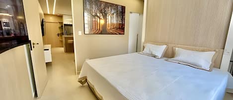 Una habitación de hotel moderna con una cama grande, un cuadro en la pared y un cabecero de madera.