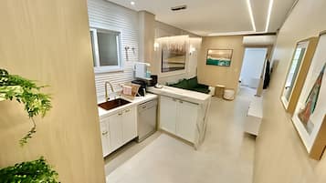 Una cocina moderna con armarios blancos, una isla central y un ventanal sobre el fregadero.