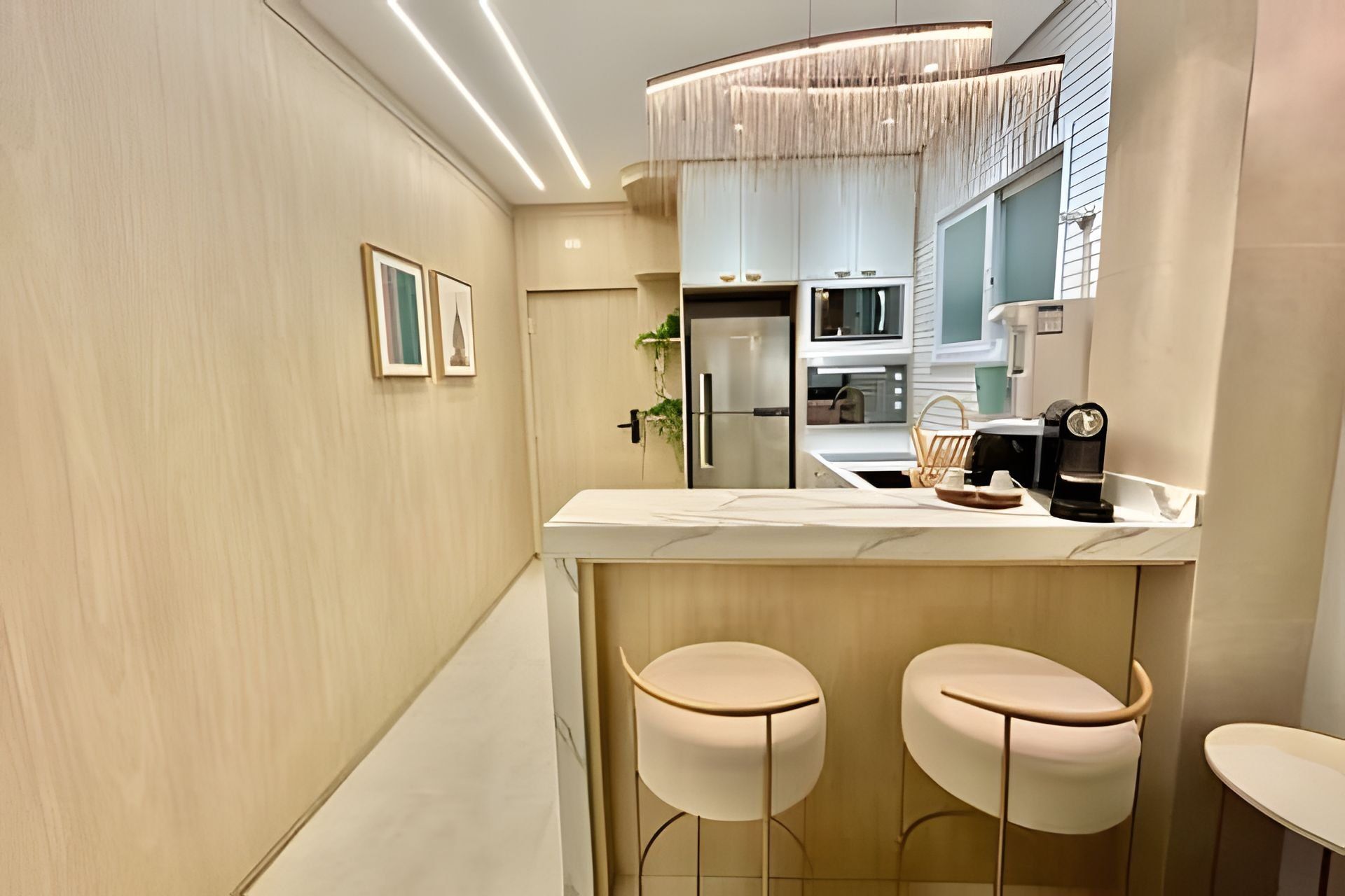 Una cocina moderna con una isla central, taburetes de bar y una lámpara colgante.