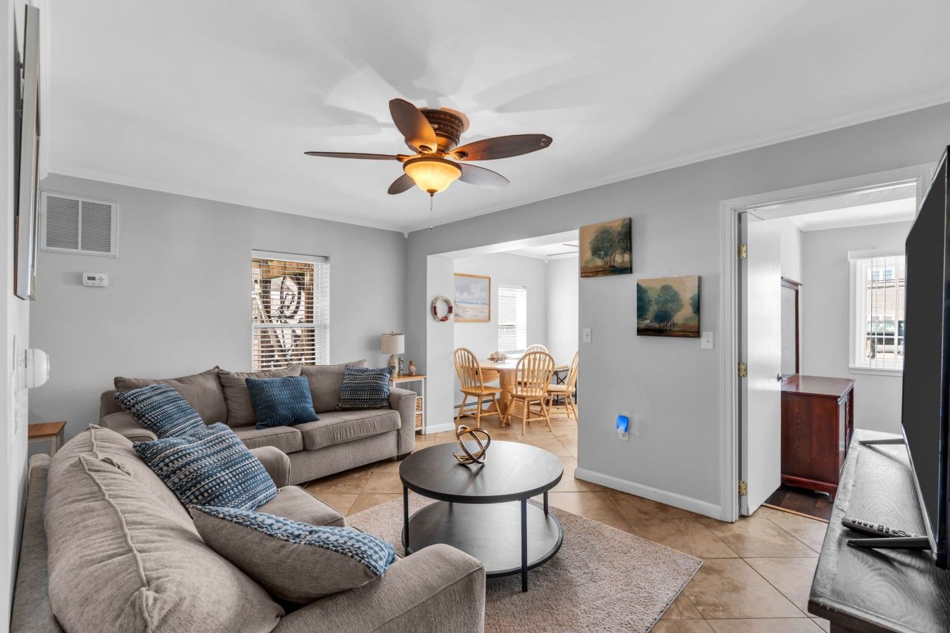 A living room with a ceiling fan, a sofa, a coffee table, and a television.