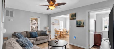 A living room with a ceiling fan, a sofa, a coffee table, and a television.