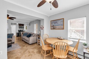 Eine moderne Küche mit Einbauofen und Mikrowelle, ein Essbereich mit Holztisch und Stühlen sowie ein Wohnzimmer mit Sofa und Deckenventilator.