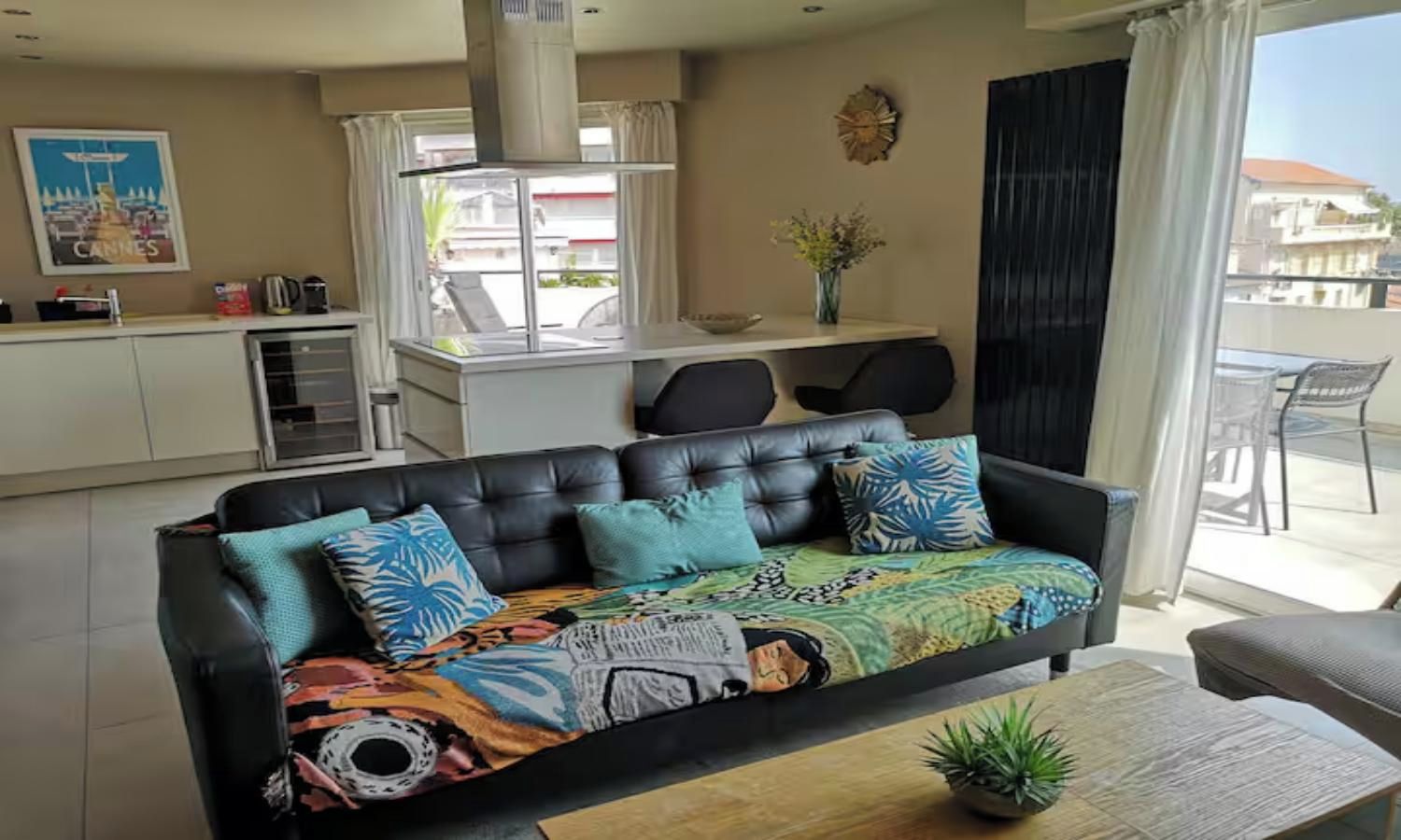 A living room with a black leather sofa, a coffee table, and a view of the outside.