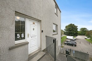 A building with a white door marked with the number 56, a small window, and a balcony with a metal railing. - Spital Lodge - Grampian Lettings (Aberdeen)