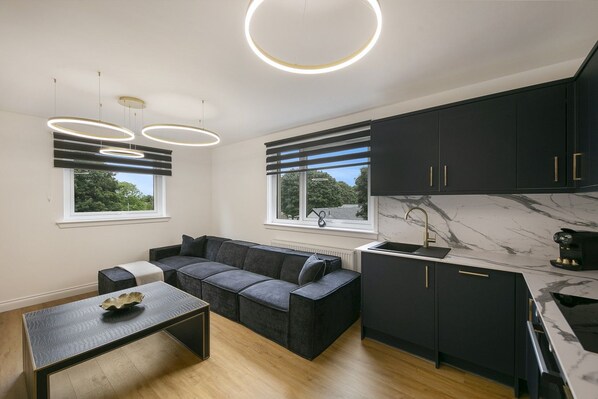 A modern kitchen with black cabinets, a marble countertop, and a built-in sink.