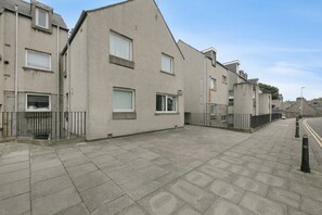 A row of residential buildings with a paved walkway and a clear sky. - Spital Lodge - Grampian Lettings (Aberdeen)
