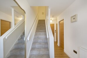 A staircase with carpeted steps, white walls, and wooden doors. - Spital Lodge - Grampian Lettings (Aberdeen)