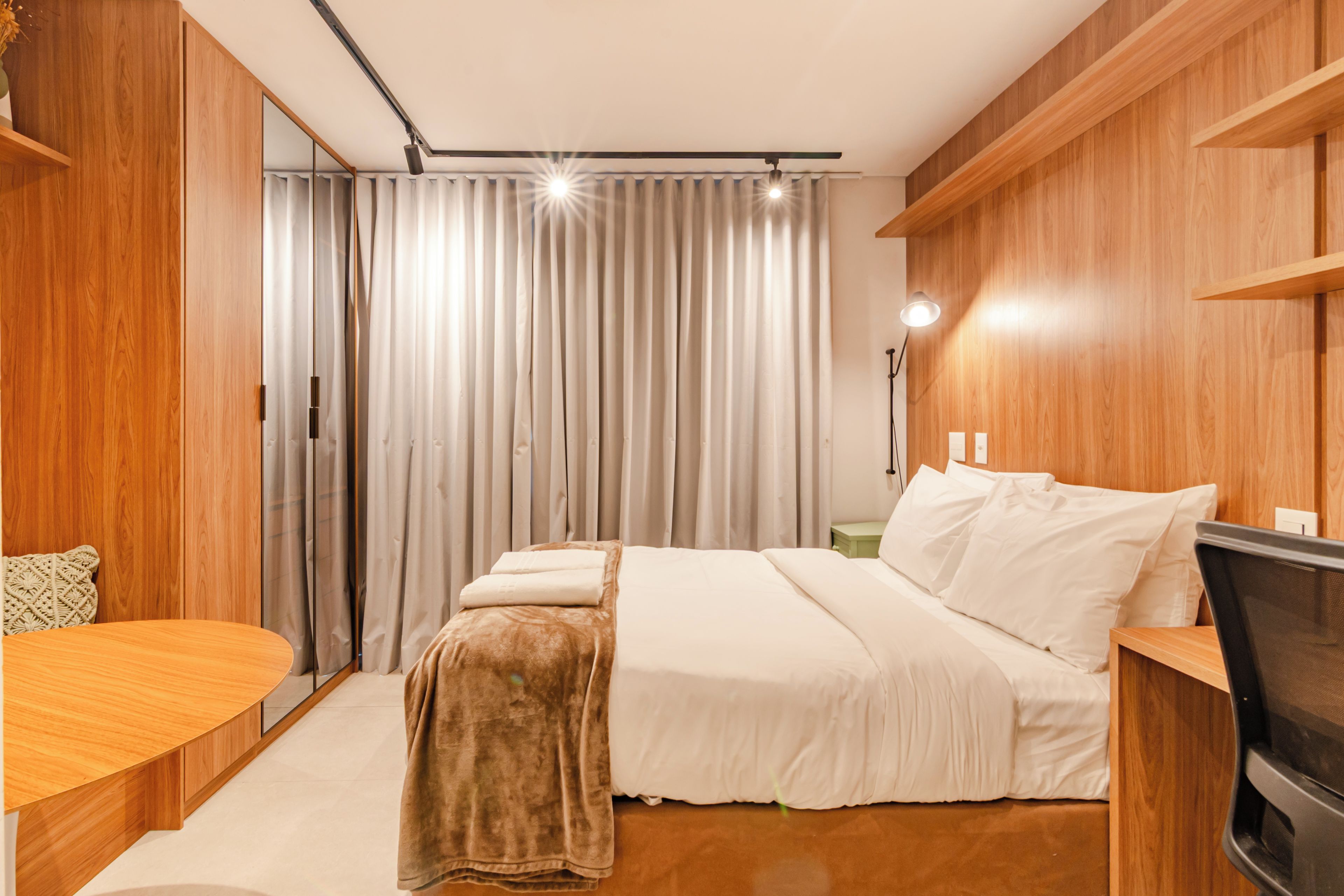 Une chambre moderne avec un grand lit, un bureau en bois et un téléviseur.